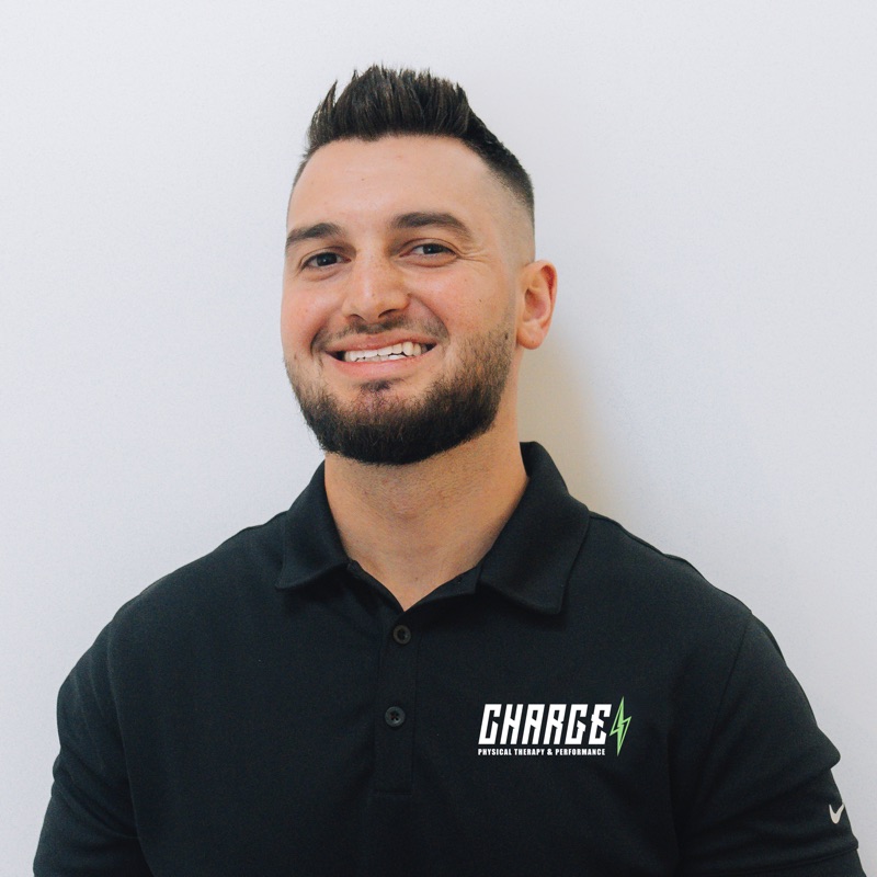 Studio headshot of Dr. Matt Feder, DPT, CSCS, smiling in a black Charge Physical Therapy polo
